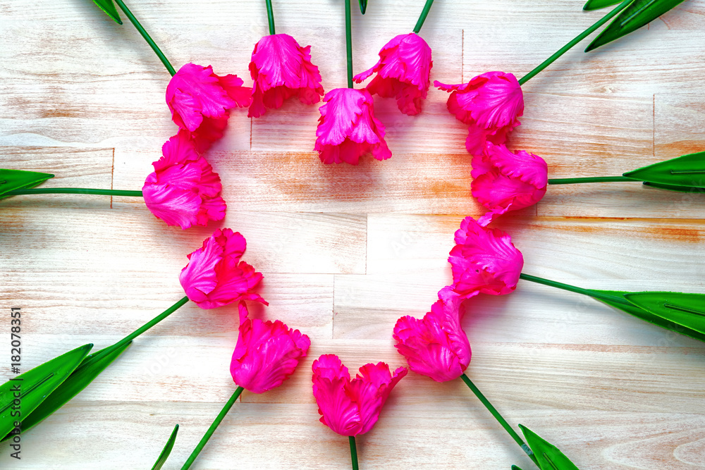 pink tulips shaped as a heart on wooden background