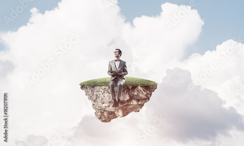 Young businessman or student floating in sky and studying the sc