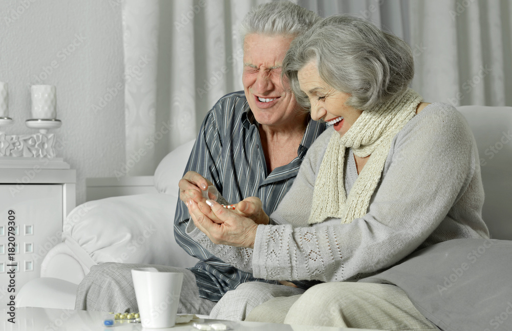 Obraz premium Ill senior couple taking pills