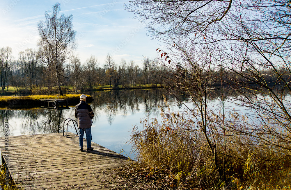 Man standing on a jetty by a lake enjoying the scenery. Man standing on a jetty by a lake enjoying the scenery.