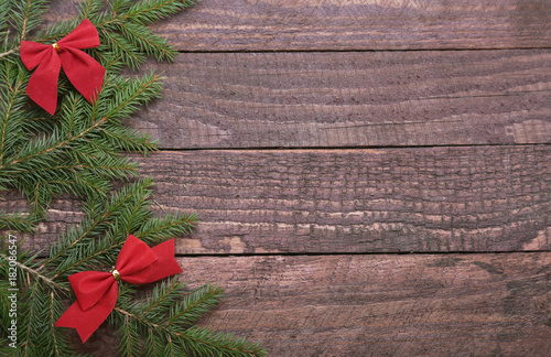 Christmas tree decorated red bow  branches and cones on wooden background