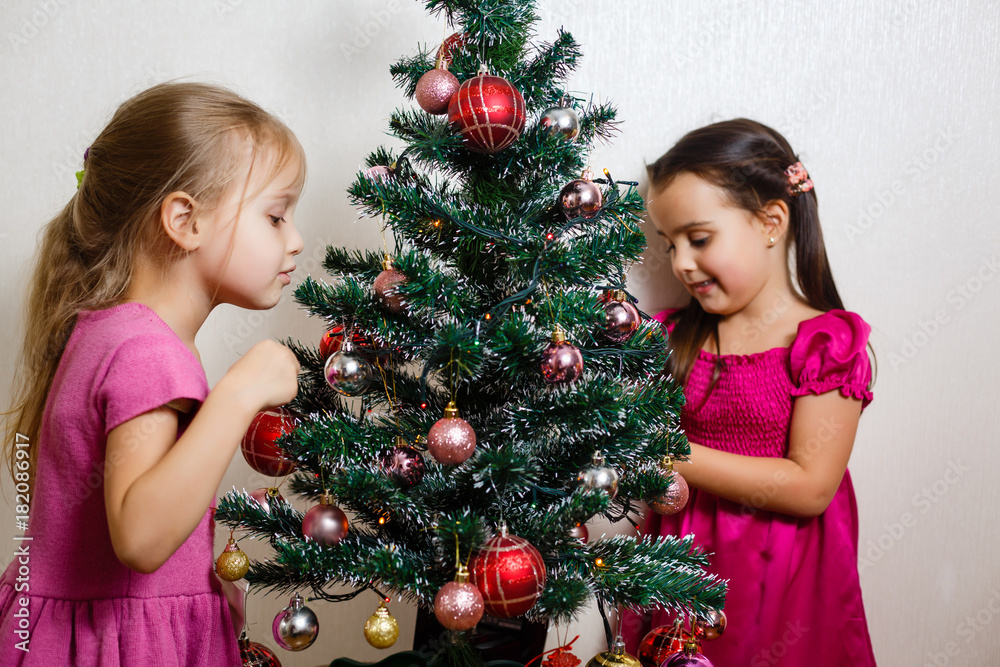 Two little sisters decorating Christmas tree. Two little sisters decorating Christmas tree.