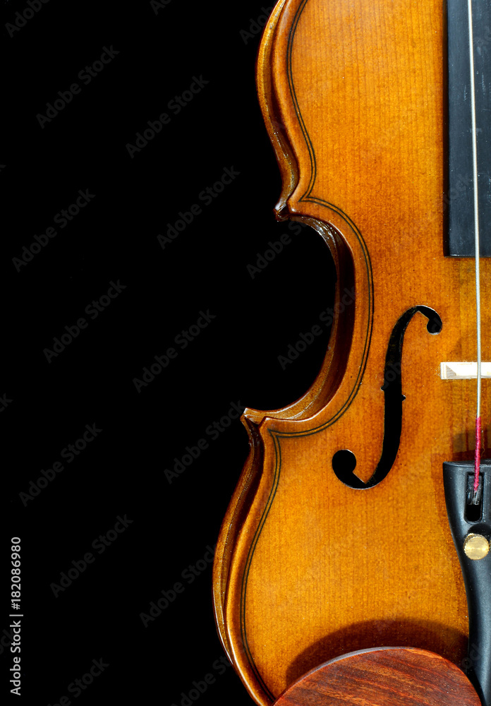 Closeup detail of miniature violin on black background includes a sound hole, chin rest and features the beautiful curves of the wooden instrument Closeup detail of miniature violin on black background includes a sound hole, chin rest and features the beautiful curves of the wooden instrument