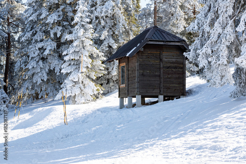 Log cabin, shelter is among snow covered pines in the winter mountains.