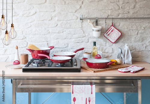 modern red kitchen behind brick wall with red cookware set photo