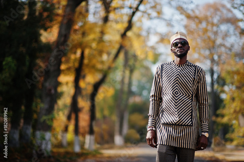 Portrait of stylish black african american man at hat and sunglasses against sunny autumn fall background. Rich people in africa at traditional dress. © AS Photo Family