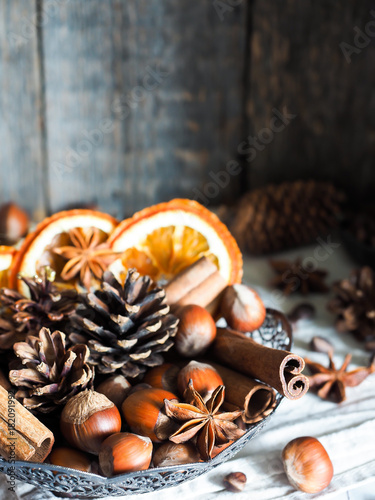 Winter ingredients nuts, cones, oranges, cinnamon star anise in a bowl. Rustic style