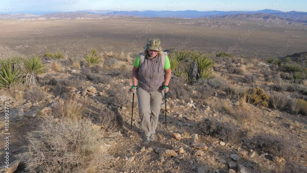 Woman Goes Up To The Hill Along The Trail In The Mojave Desert, Front View Woman Goes Up To The Hill Along The Trail In The Mojave Desert, Front View