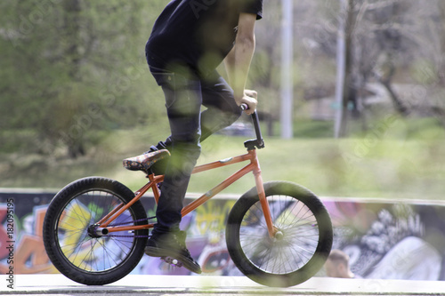 Side Profile Photo of BMX Rider in colorful grafitti skate park red bike pedaling © Adam