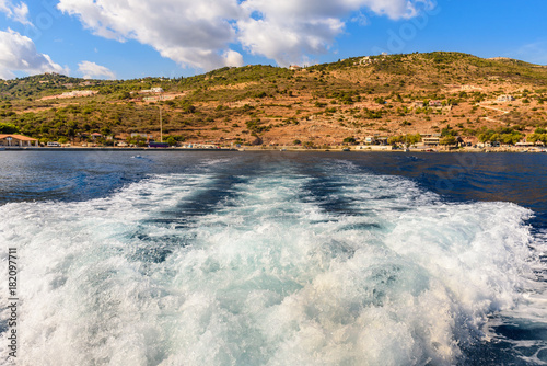 Water trail foaming behind a cruise boat. Bay of Agios Nikolaos on Zakynhos island. Greece.