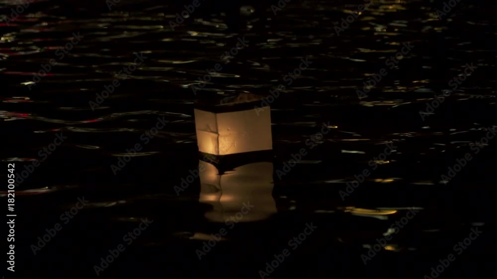 The light of paper lanterns floating on the water of Vltava illuminating the dark of Prague