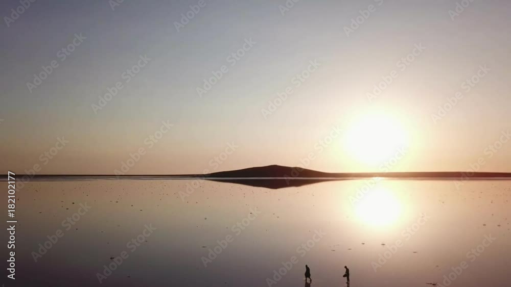Arial of view from drone when people walk and run around the salt pink lake at sunset in the backlight in 4K Arial of view from drone when people walk and run around the salt pink lake at sunset in the backlight in 4K