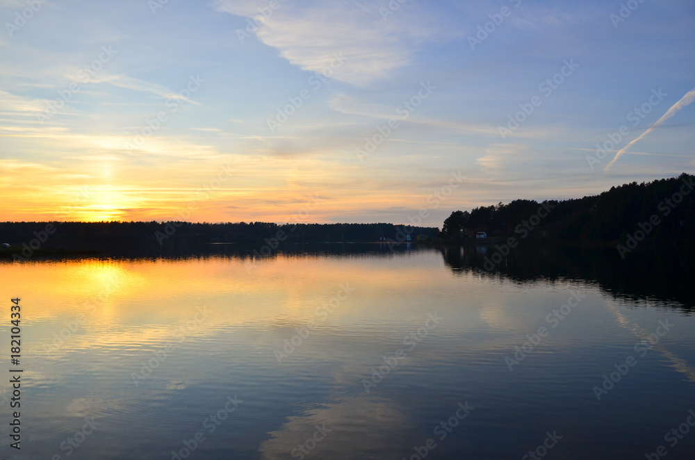 Beautiful orange sunset over the lake with sky reflected in the water