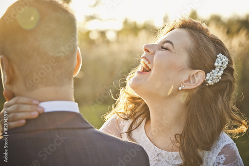 a young bride laughs and yells in the ear of the groom