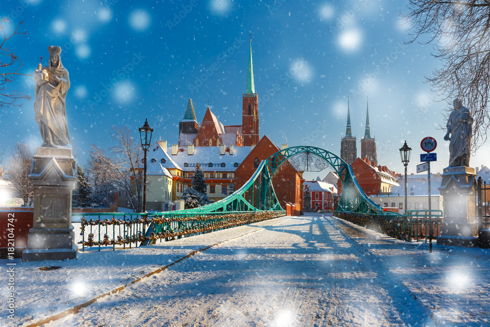 Fototapeta premium Tumski Bridge and Island with Cathedral of St. John and church of the Holy Cross and St. Bartholomew in the snowy overcast winter day in Wroclaw, Poland