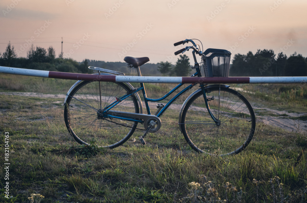 Fototapeta premium Old vintage bike on the meadow against sunset sky