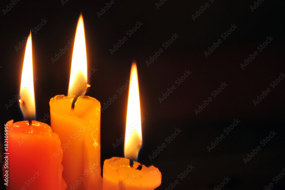 Three candles on dark background