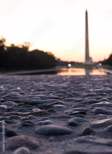 Closeup of DC Monument from low vantage point-pebble concrete with blurred monument in background at sunrise - vertical orientation Washington DC United States of America U.S. 