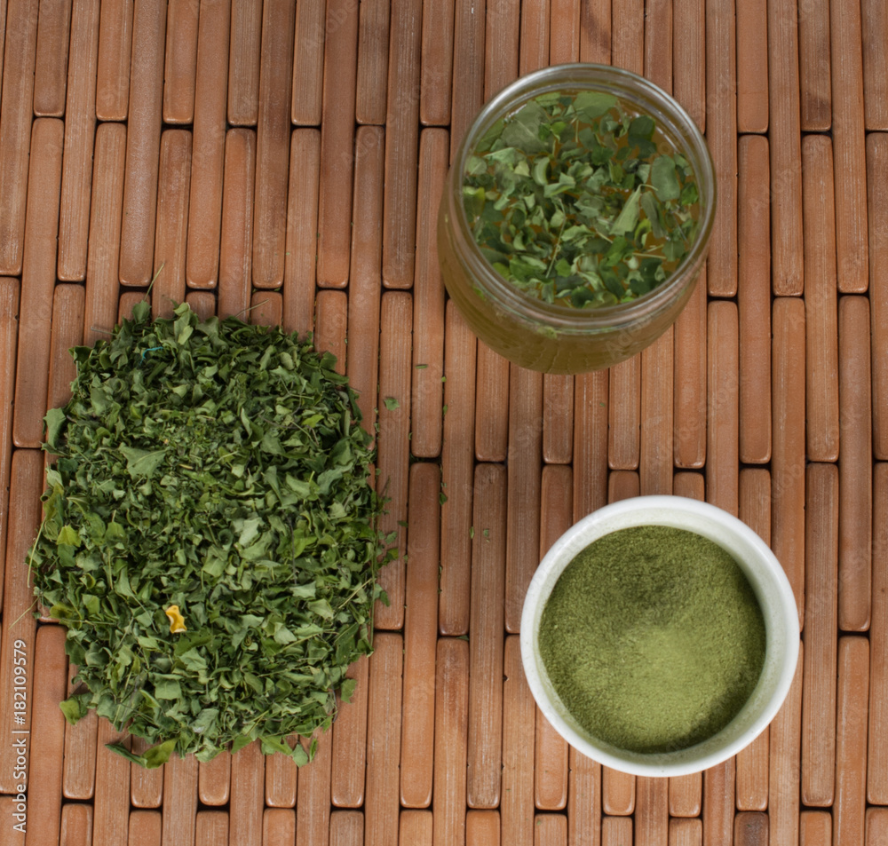 Moringa leaves with juice in a glass on wooden background Moringa leaves with juice in a glass on wooden background