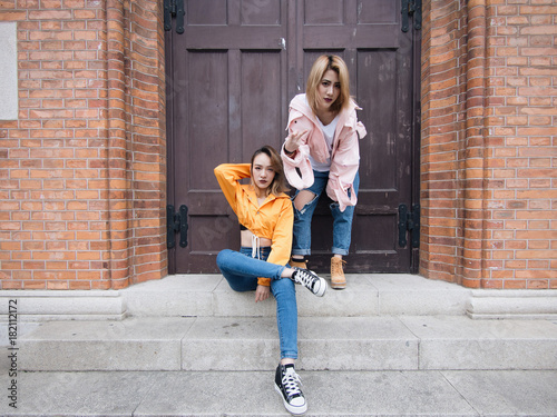 Two fashion Chinese girls making poses in front of a retro style wooden door in Shanghai bund. photo