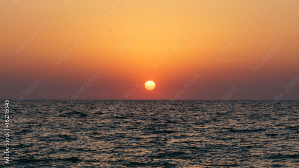 Sunset on the sea in clear weather with the sun disk