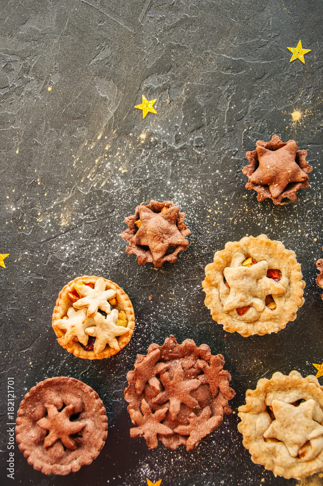 Fototapeta premium Different sizes of traditional Christmas dessert - Mince pies. Vanilla and chocolate pastry. Black backdrop.Top view.