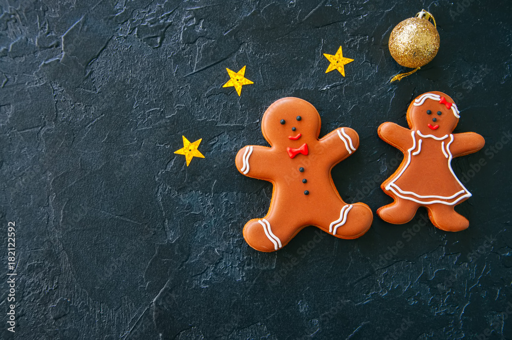 Festive Christmas background, Gingerbread man and girl cookies, stars and ball on a black stone background. Top view with copy space