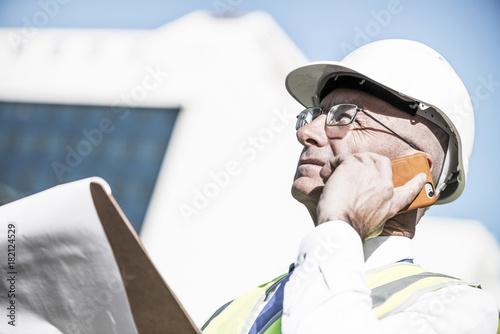 Man architector outdoor at construction area having mobile conve photo