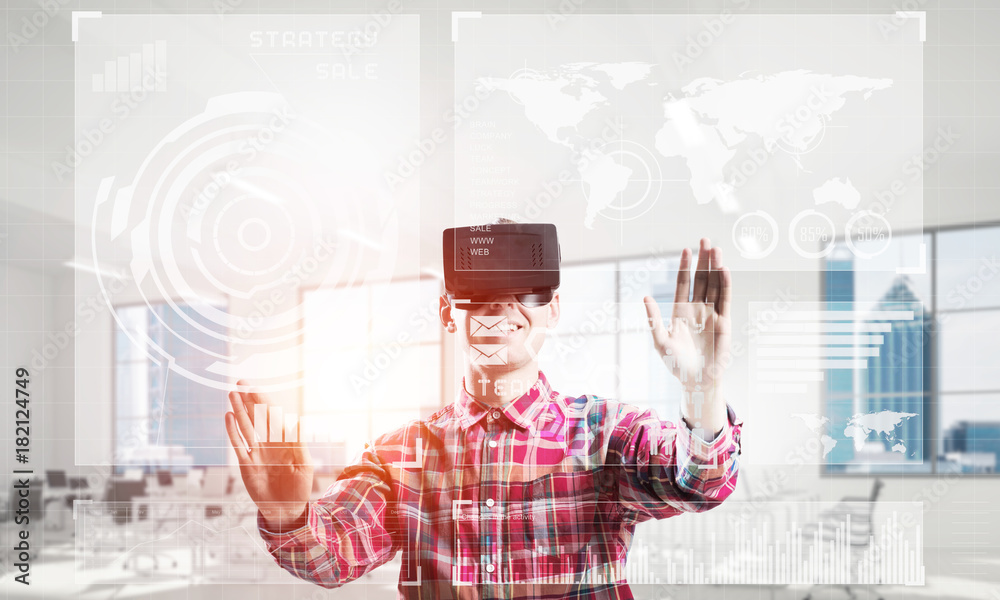 Young man in modern office interior experiencing virtual reality technology Young man in modern office interior experiencing virtual reality technology