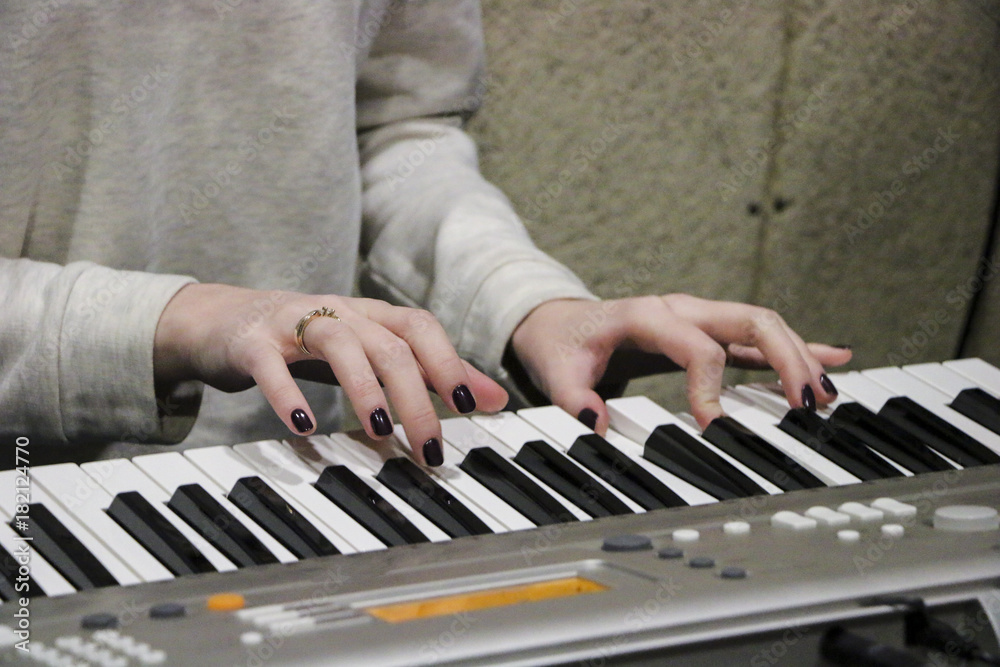 Obraz premium A young girl pianist plays the electronic piano with her favorite music. Female graceful hands touch the keys of the synthesizer close-up.