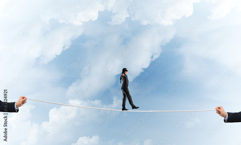 Business concept of risk support and assistance with man balancing on rope Business concept of risk support and assistance with man balancing on rope