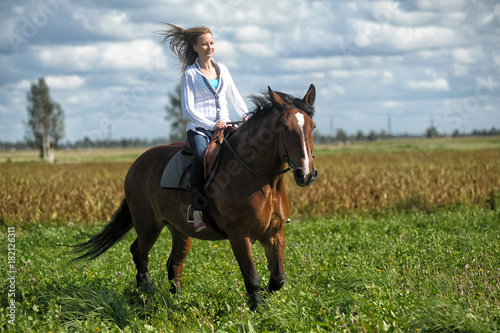 blonde in a field on a brown horse photo