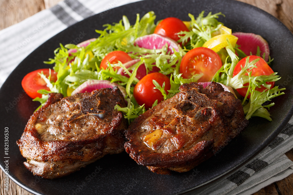 Roasted lamb steak and salad from radish, tomatoes, pepper and lettuce close-up. horizontal