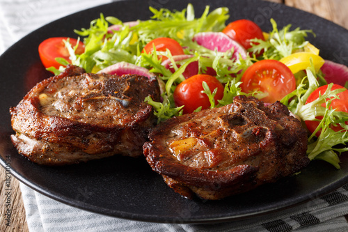 Spicy delicious lamb steak and salad from radish, tomatoes, pepper and lettuce close-up. horizontal