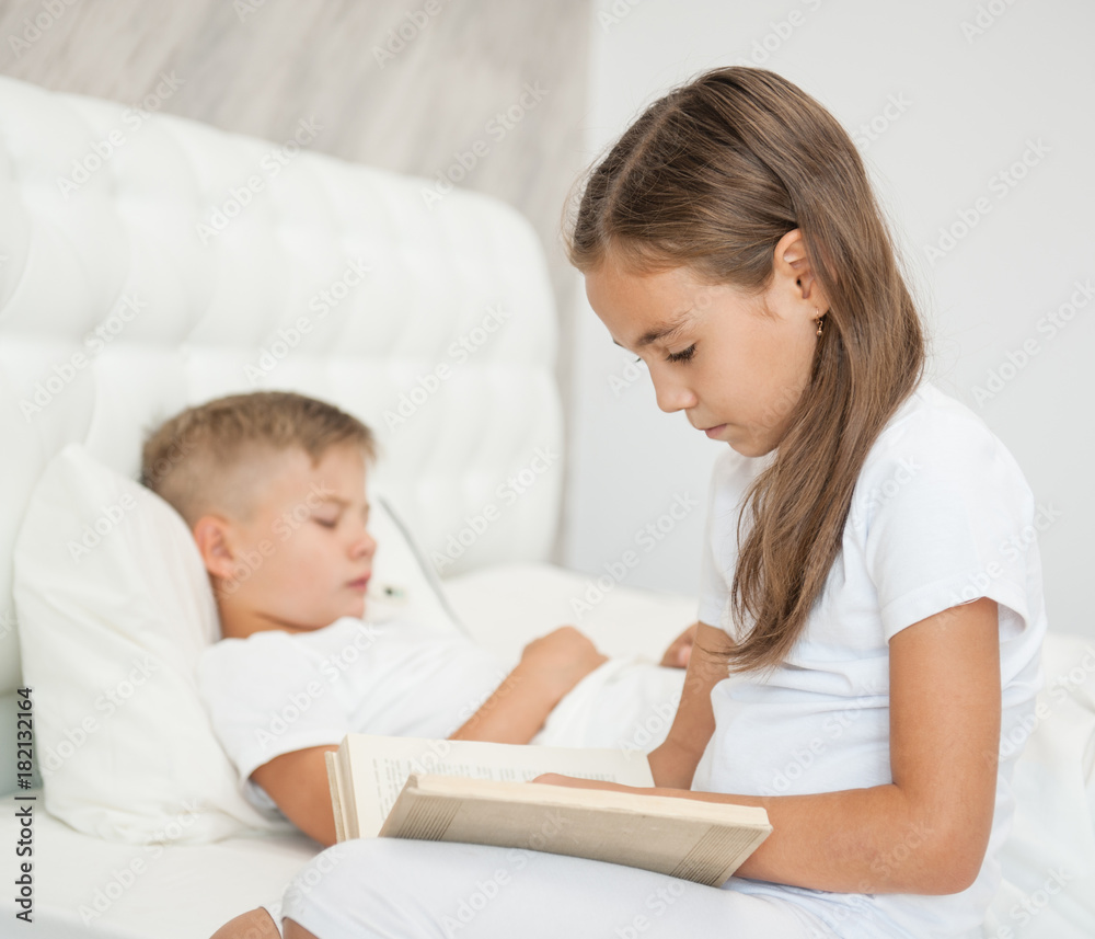 Girl reads the book to the sick brother Girl reads the book to the sick brother