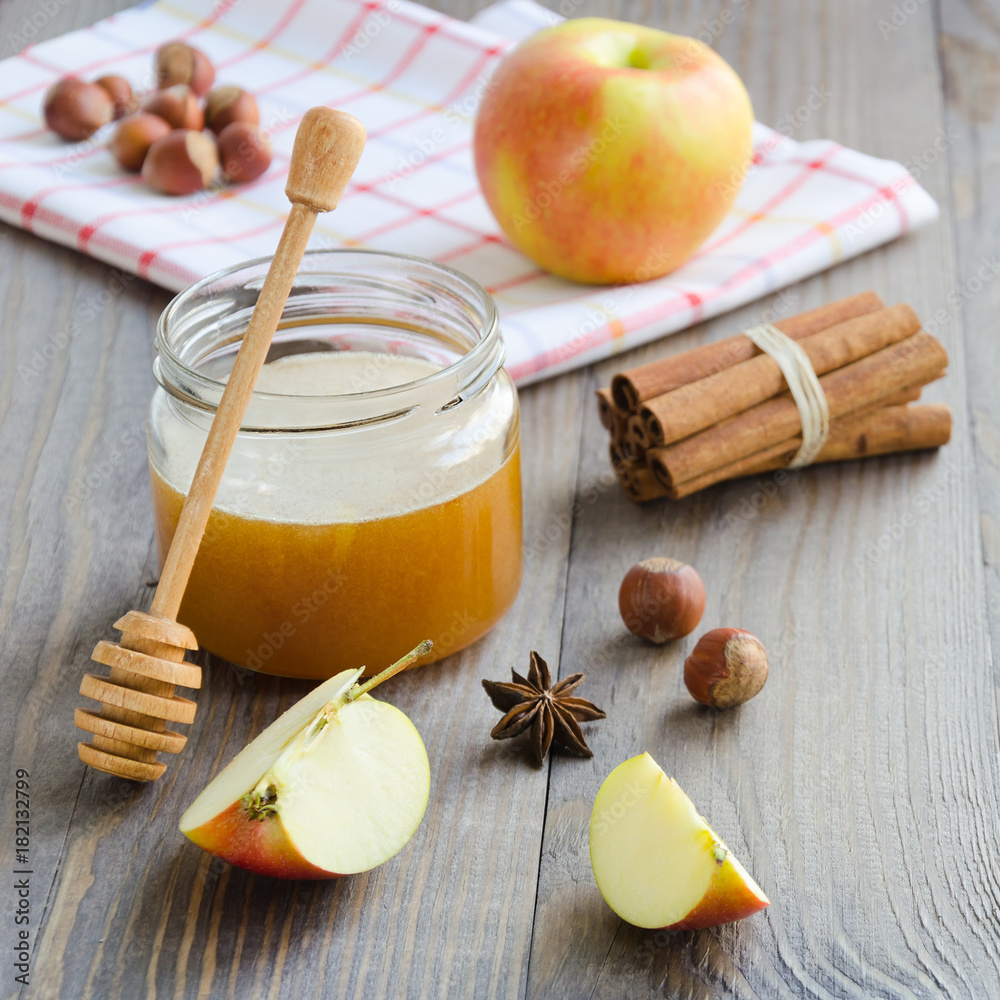Jar of honey, honey stick, cinnamon, hazelnuts and red apple Jar of honey, honey stick, cinnamon, hazelnuts and red apple