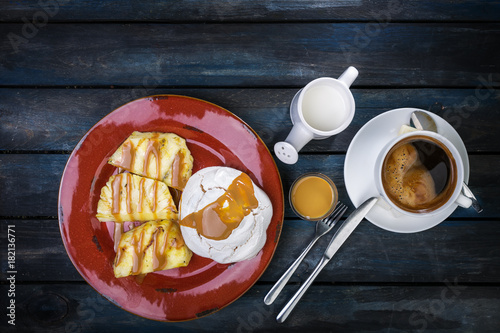 Delicious dessert. Meringue with pineapple and fresh coffee on a colored wooden background. Top view photo