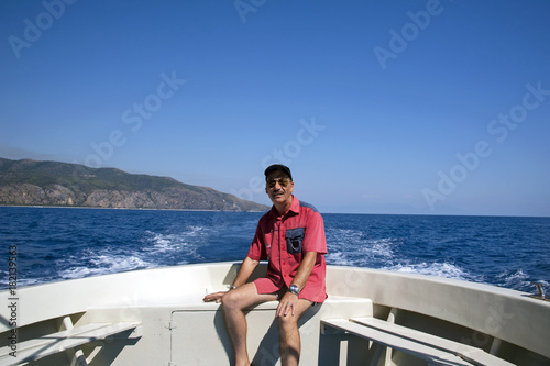 Man sat on a motorboat's stern during a boat ride, Marina di Camerota, Italy © Tony