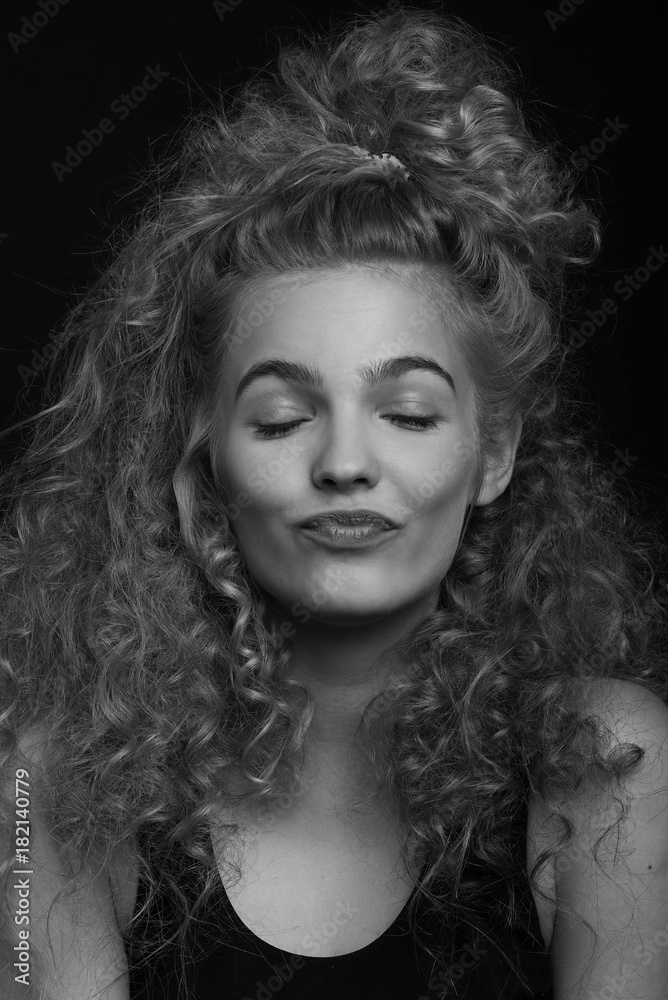 Emotive black and white studio portrait of cute young woman with curly hair.