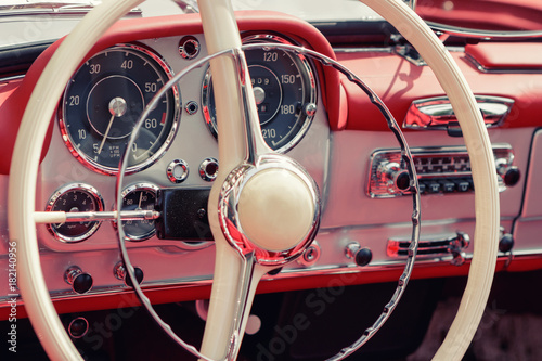 Close-up, detailed photo of the interior, dashboard, steering wheel and speedometer of a classic oldtimer luxury sports car.