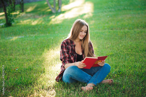pretty blond young woman reading a book at park