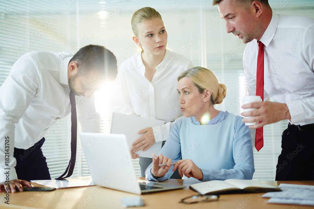 Obraz premium Mature employer discussing possible difficulties of getting online statistics with her subordinates