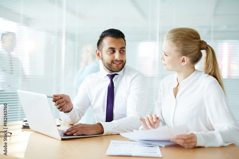 Young confident businessman making presentation of his ideas or new business strategy and discussing it with co-worker Young confident businessman making presentation of his ideas or new business strategy and discussing it with co-worker