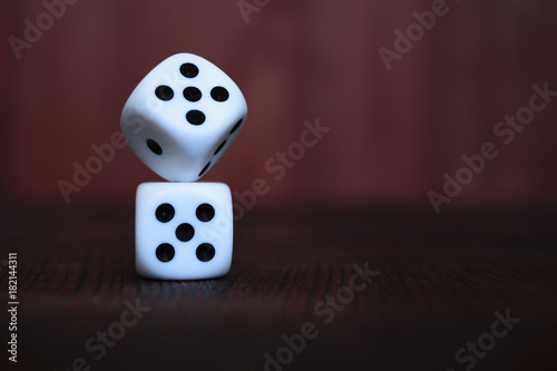 Pile of two white plastic dices on brown wooden board background. Six sides cube with black dots. Numbers 1, 3, 5.
