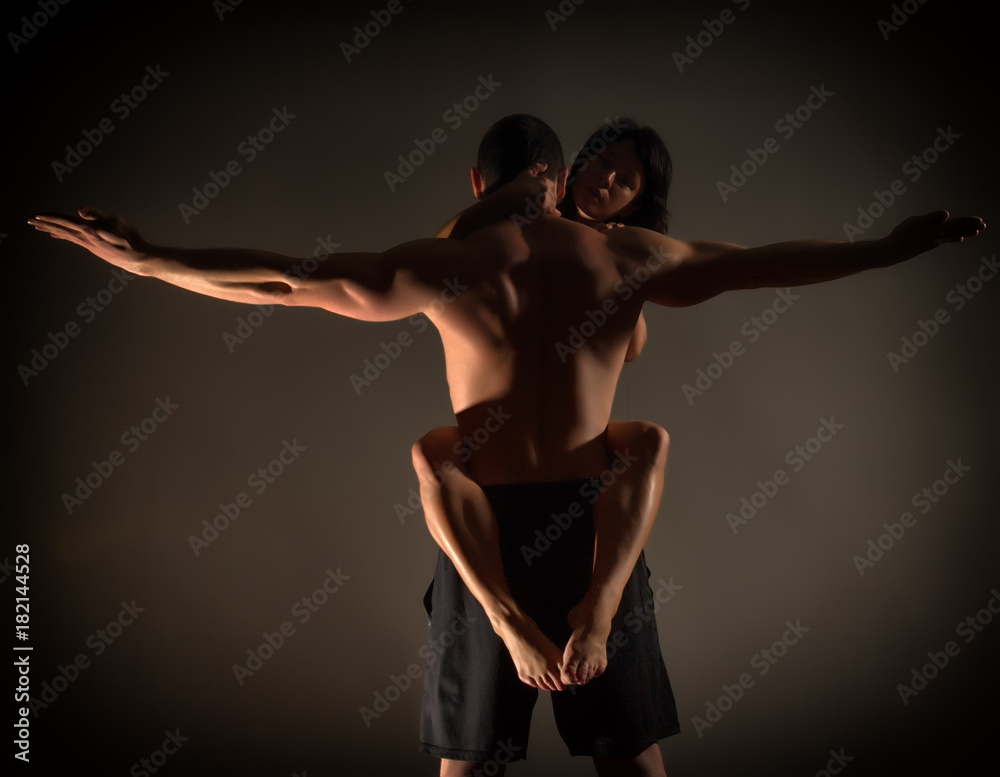 sports man and woman doing acroyoga exercises in a dark room