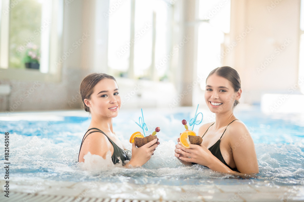 Two happy women in bikini enjoying tropical cocktails in warm water Two happy women in bikini enjoying tropical cocktails in warm water