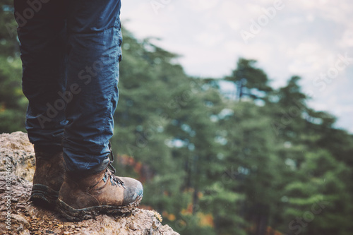 Feet on rocky cliff edge with forest aerial view Travel Fashion Lifestyle adventure vacations concept trekking boots