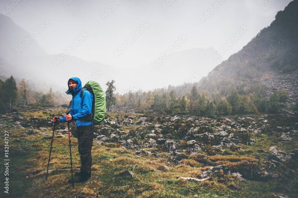 Traveler Man with backpack hiking Travel Lifestyle concept rainy cloudy mountains and forest landscape on background adventure vacations outdoor