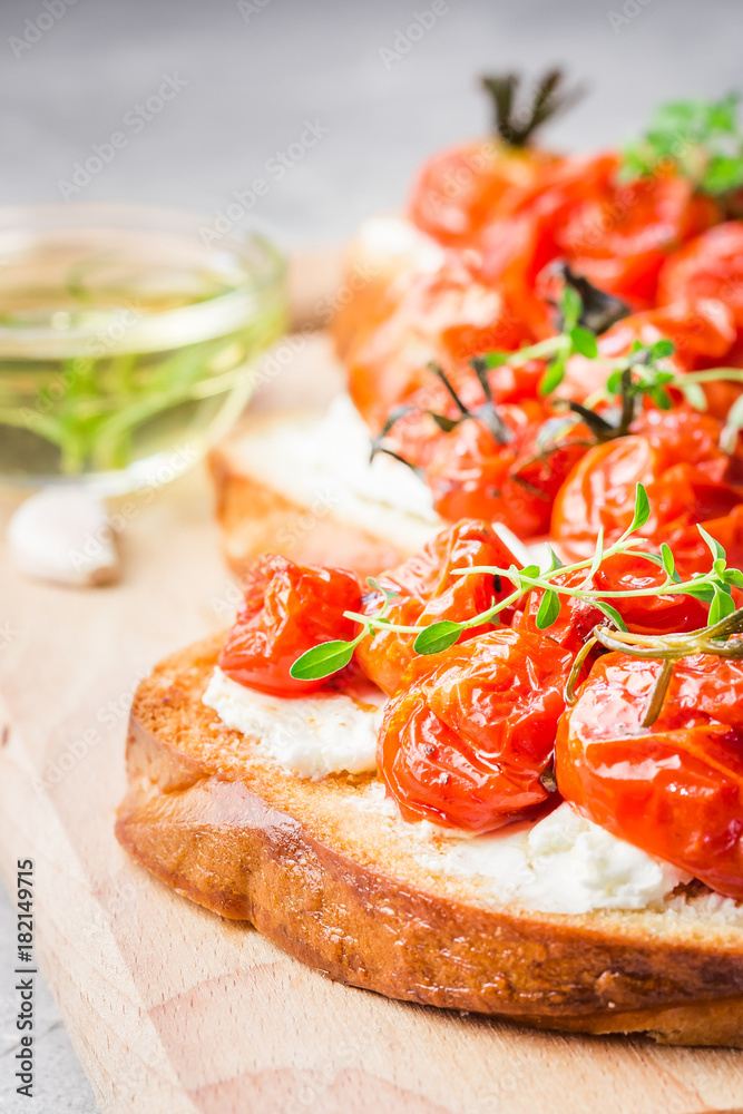 Roasted cherry tomatoes and goat cheese bruschetta. Selective focus, close up.