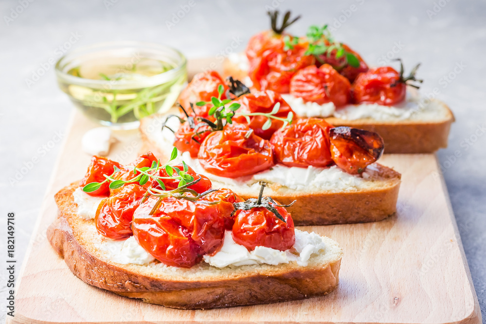 Roasted tomatoes and garlic bruschetta with ricotta cheese. Selective focus, close up.